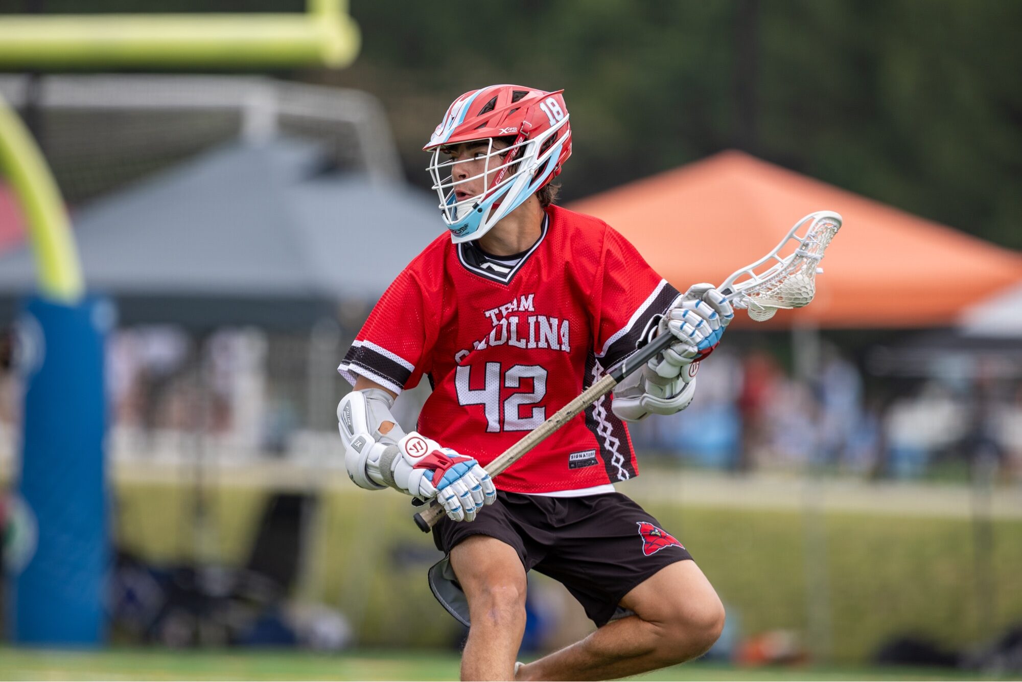 Team Carolina boys travel lacrosse player carrying the ball upfield during a summer tournament